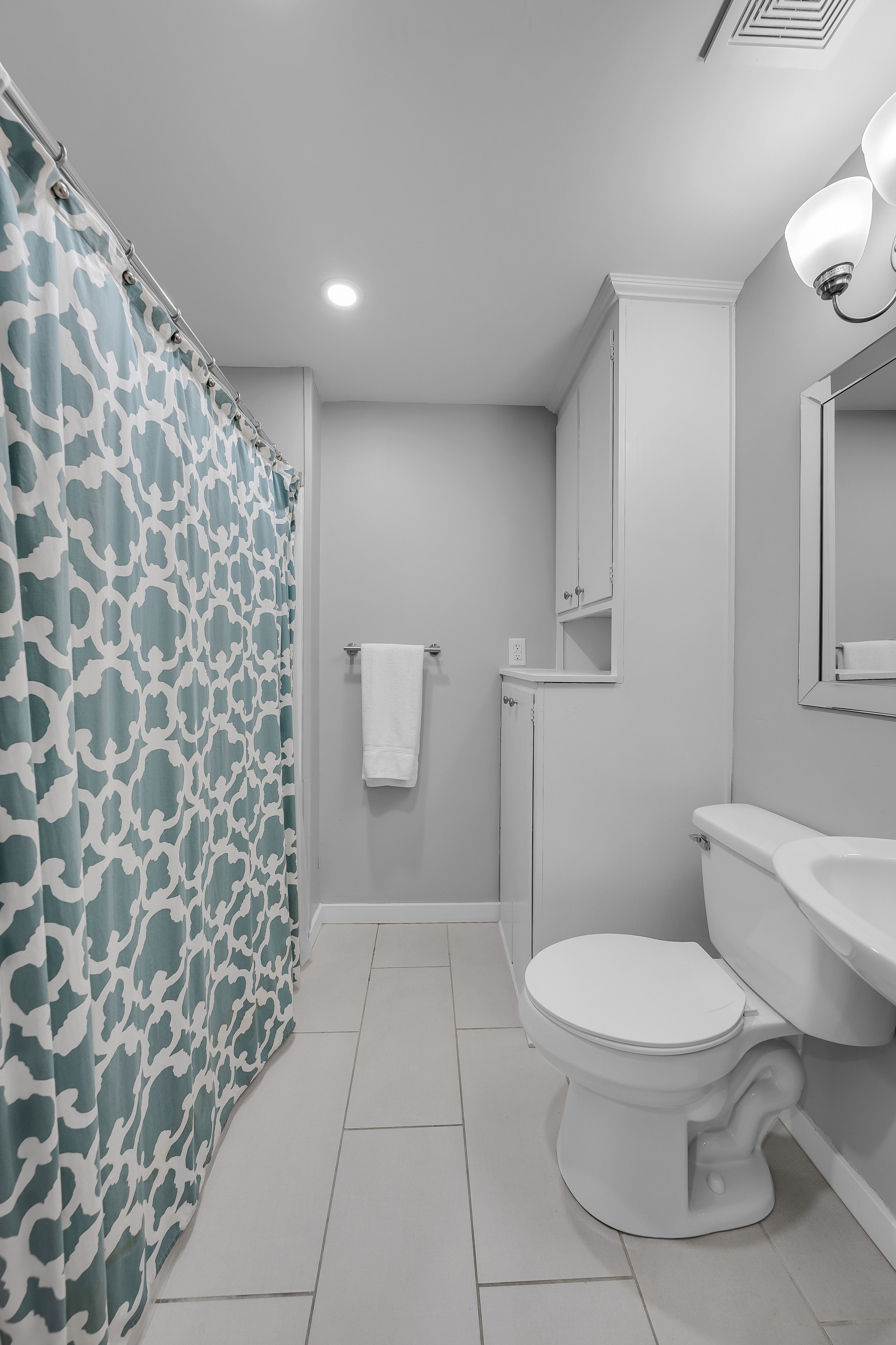 RCVRY HOUSE basement bathroom with teal shower curtain