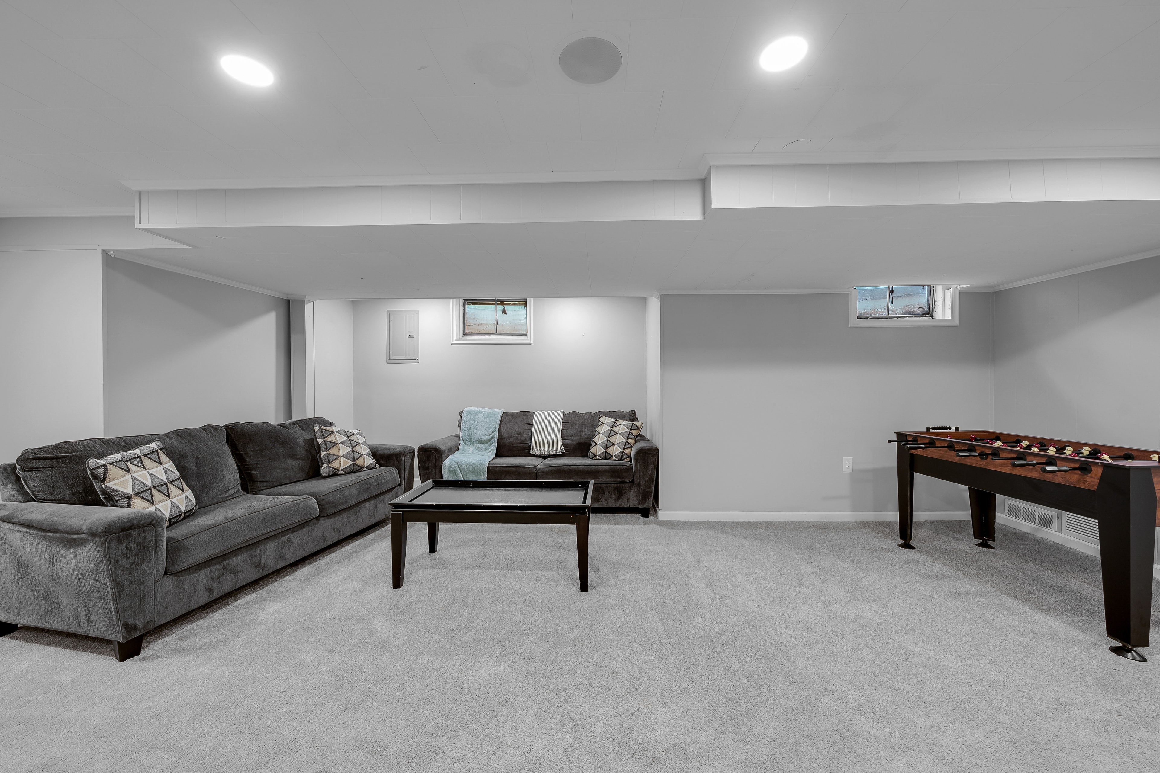 RCVRY HOUSE basement rec room from seating side — sofas and foosball table