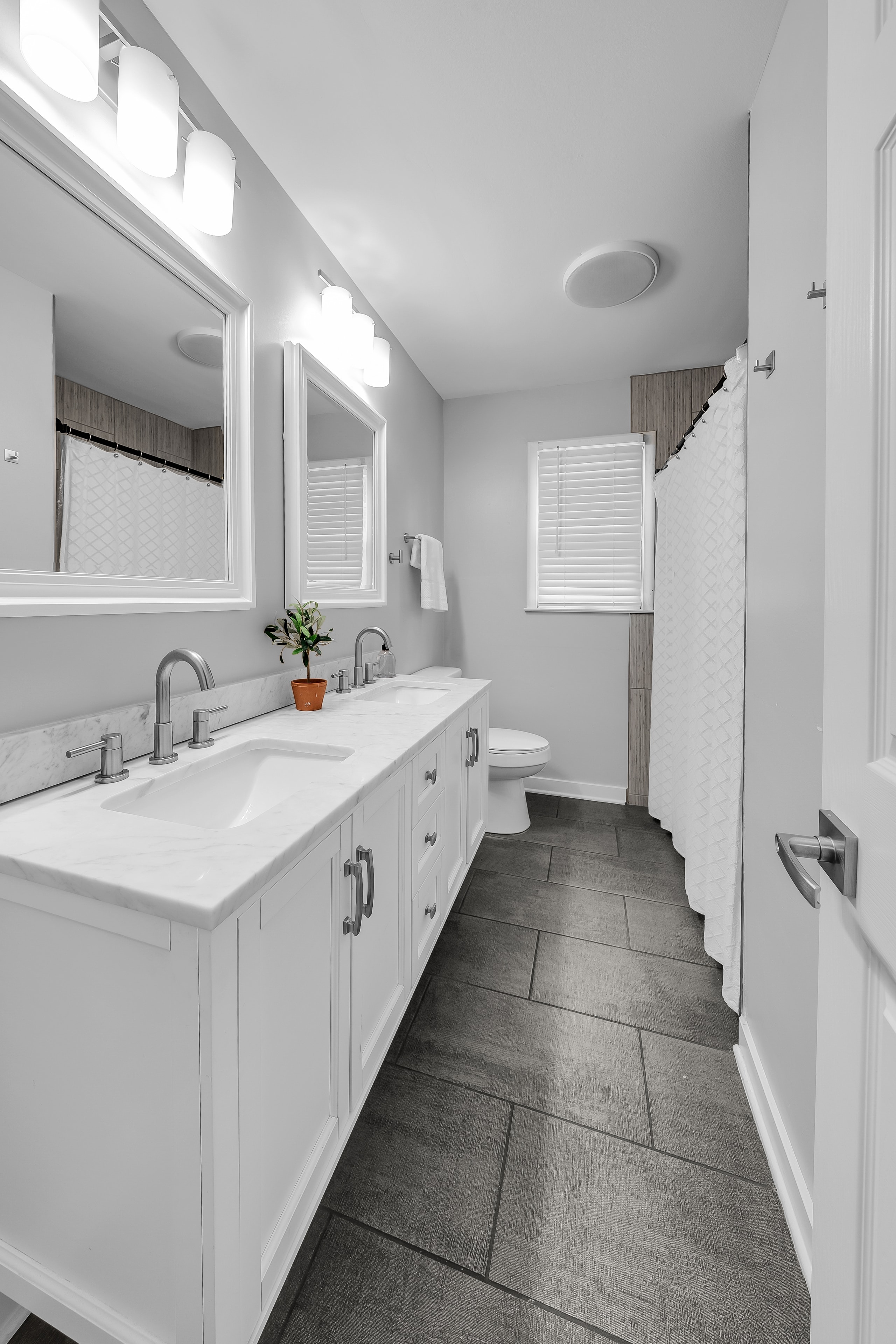 RCVRY HOUSE shared bathroom with double vanity and dark tile floor